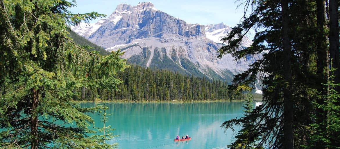A person in a boat on a lake with mountain perspectives in the background.